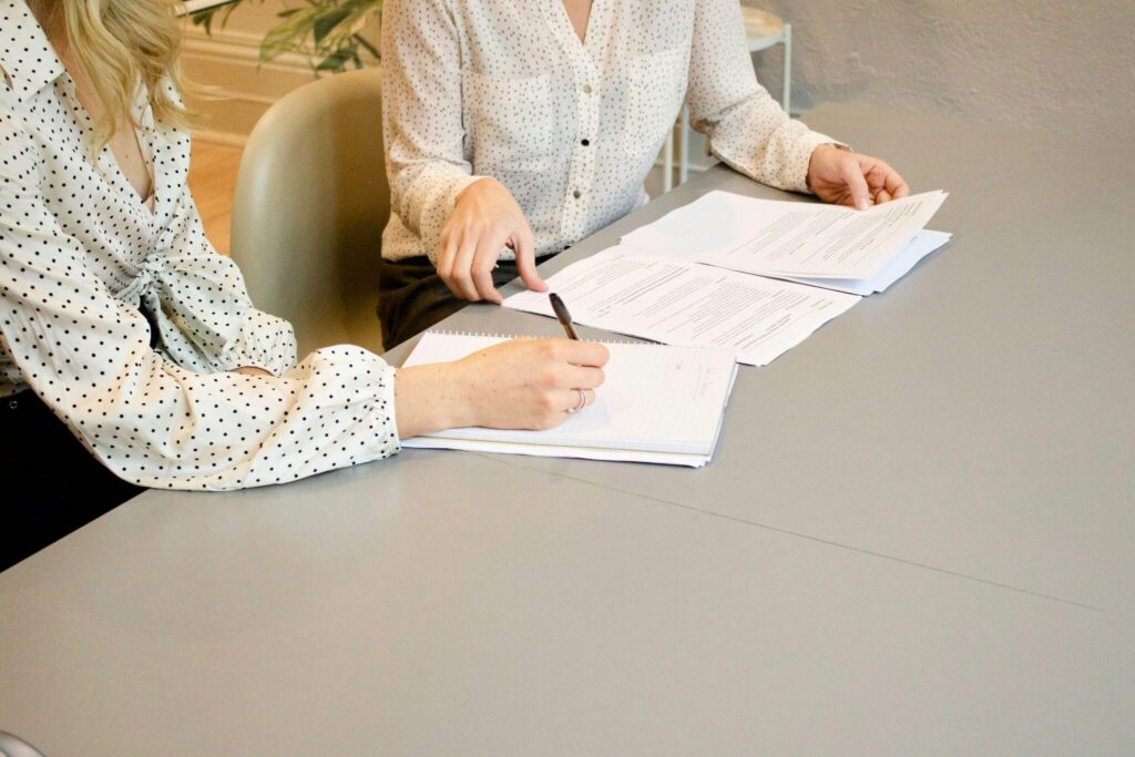 Two ladies signing documents. 