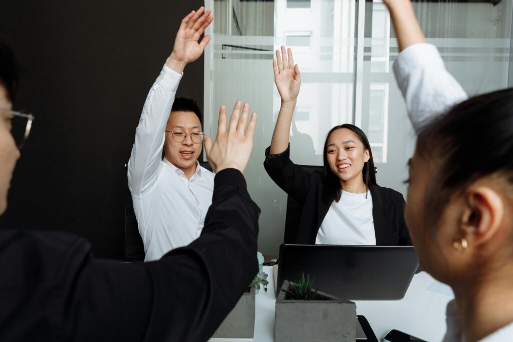 A group of professionals smiling and raising hands.