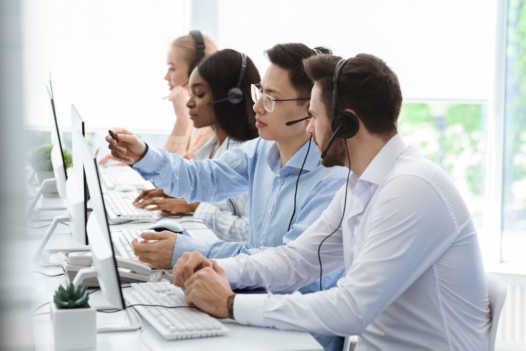 Customer support service concept. Hotline operator helping his colleague at call centre office