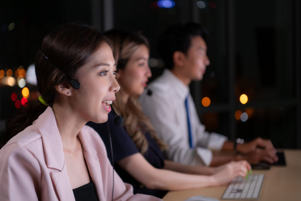 Group of broker international stock traders wearing headset working actively at night in office, Concept of customer support agent provide service on telephone.